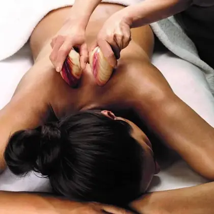 Warm lava shells massaging a relaxed client's shoulders